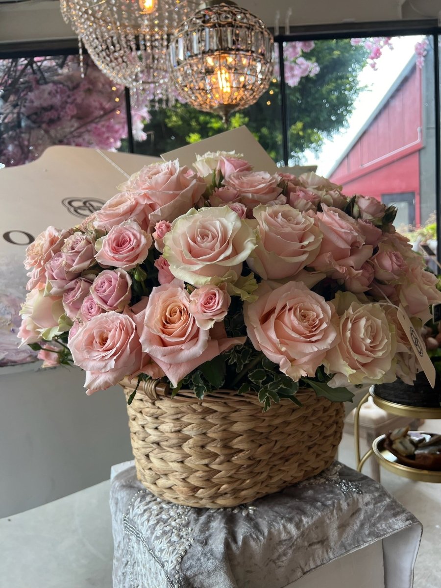 Elegant pink rose bouquet in natural woven basket with crystal chandelier background