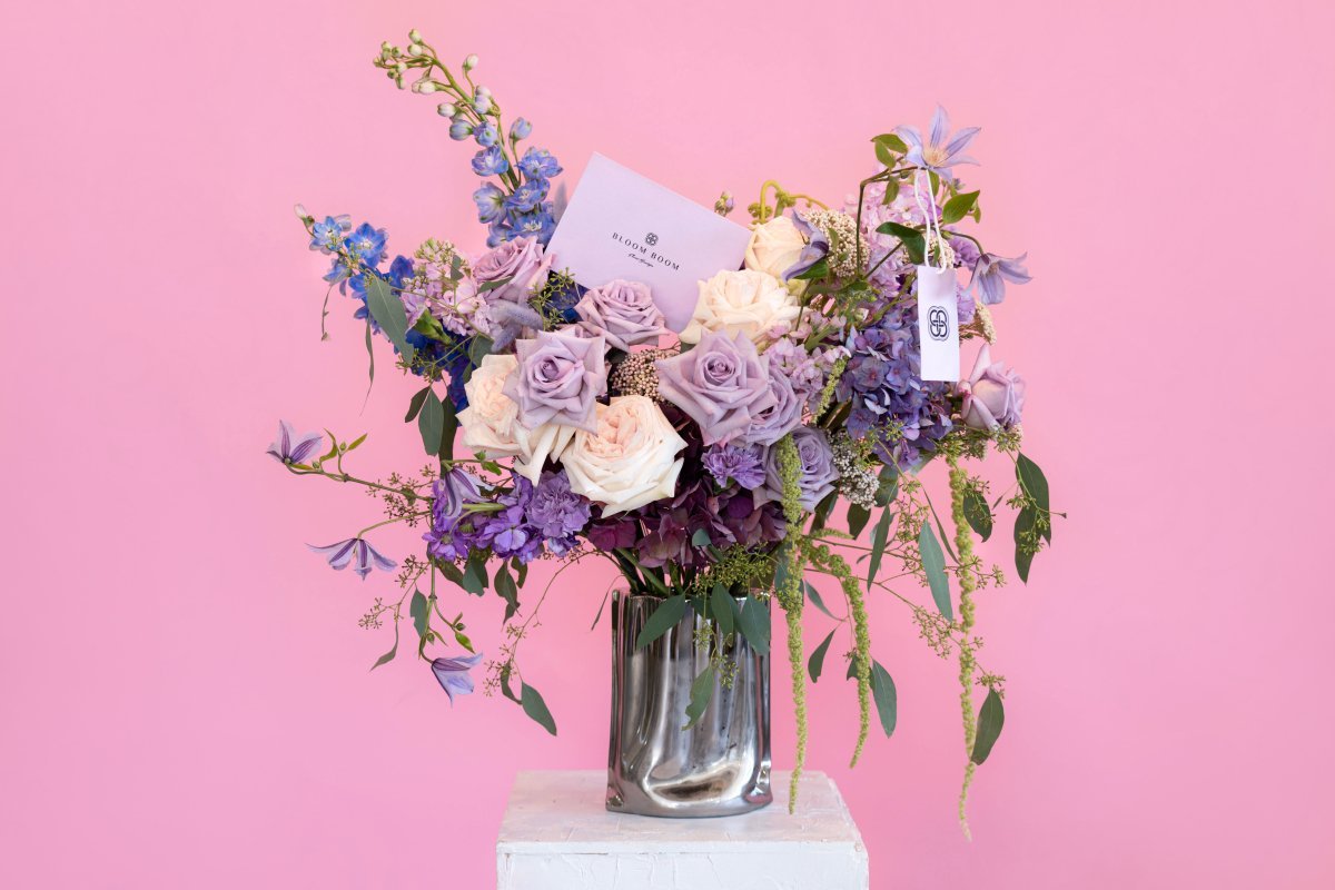 Luxury purple and cream rose bouquet with blue delphiniums and greenery in silver metallic vase