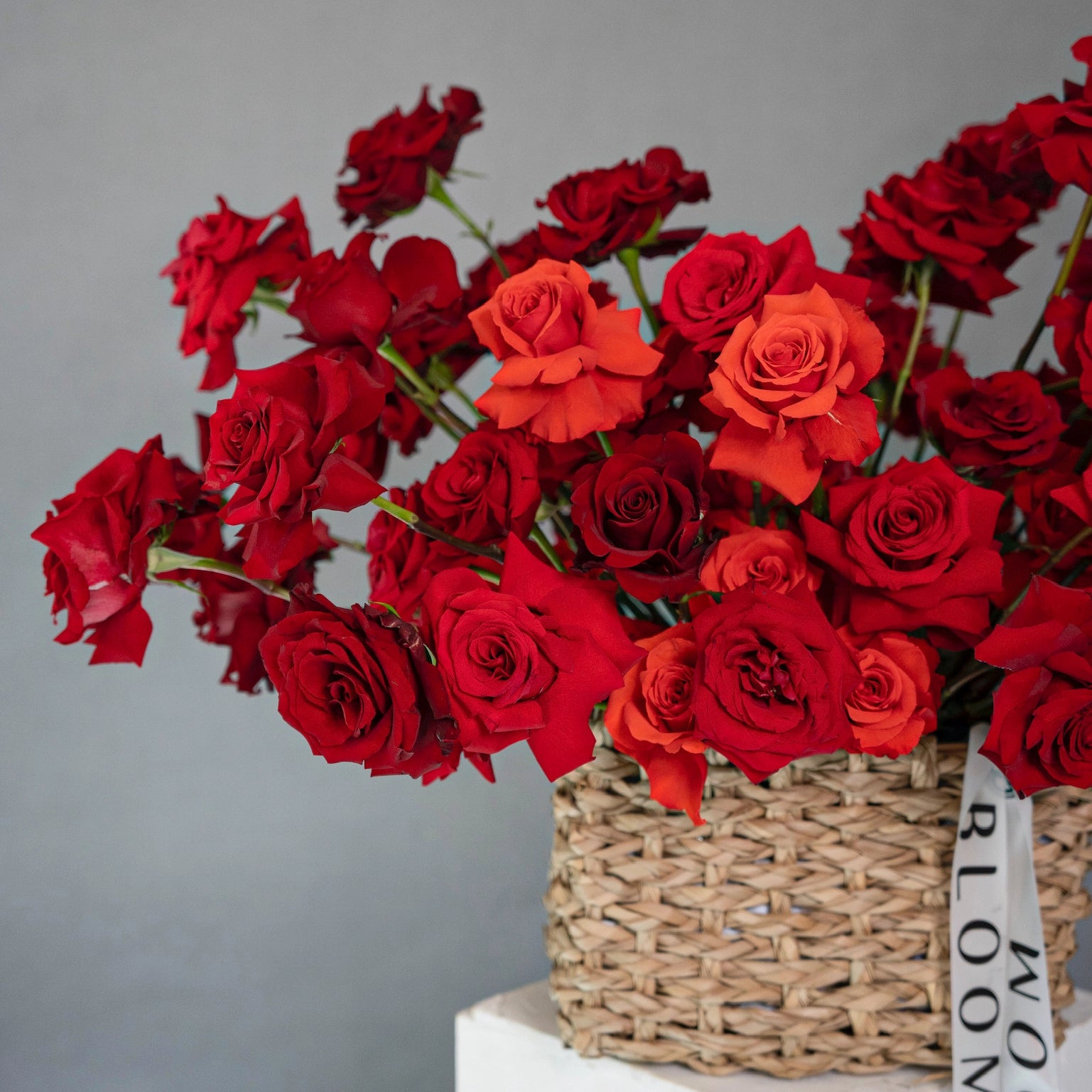 Red and coral roses in wicker basket arrangement featuring deep red and bright orange roses for Los Angeles delivery
