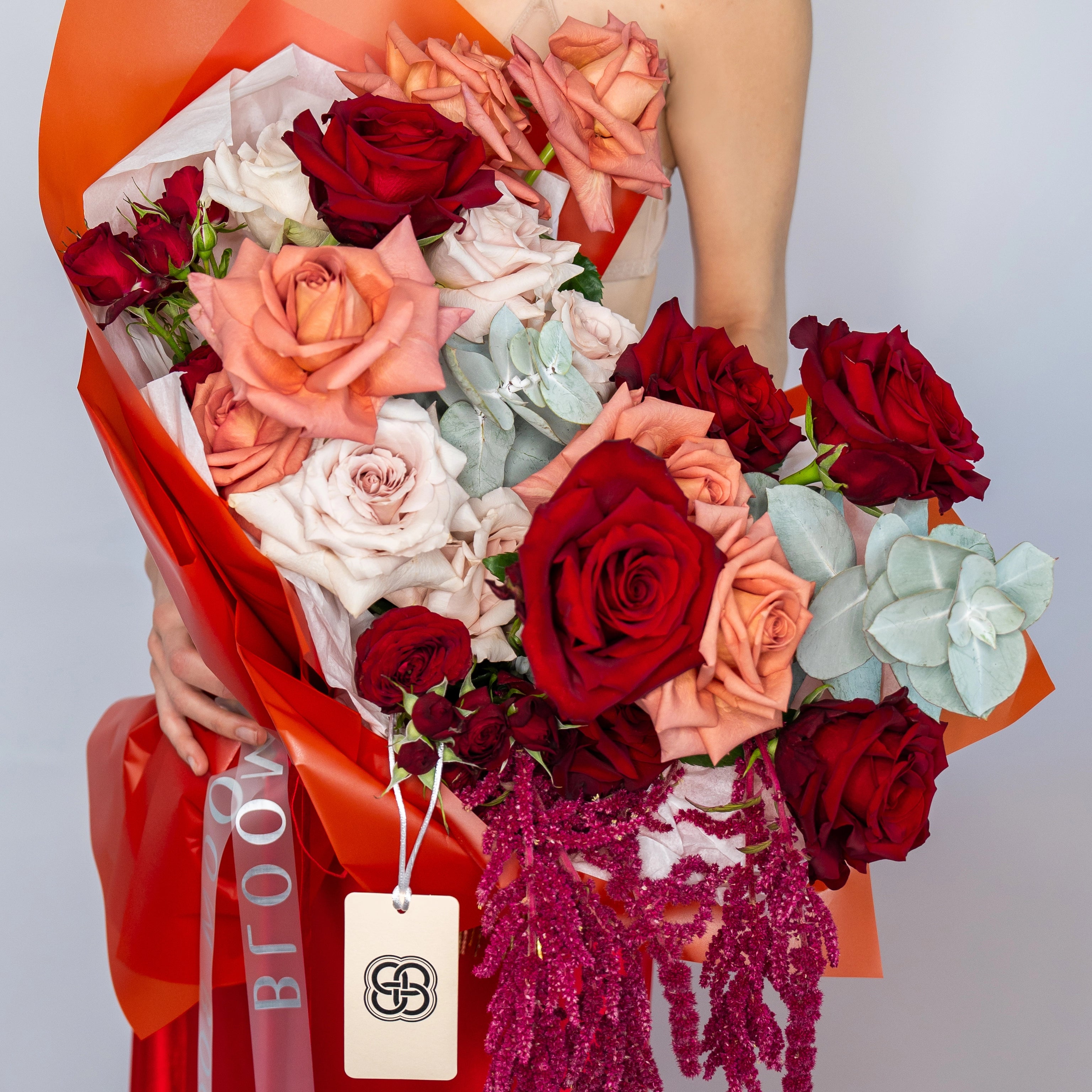 Mixed rose bouquet with red, coral, peach and white roses wrapped in orange paper - Los Angeles flower delivery