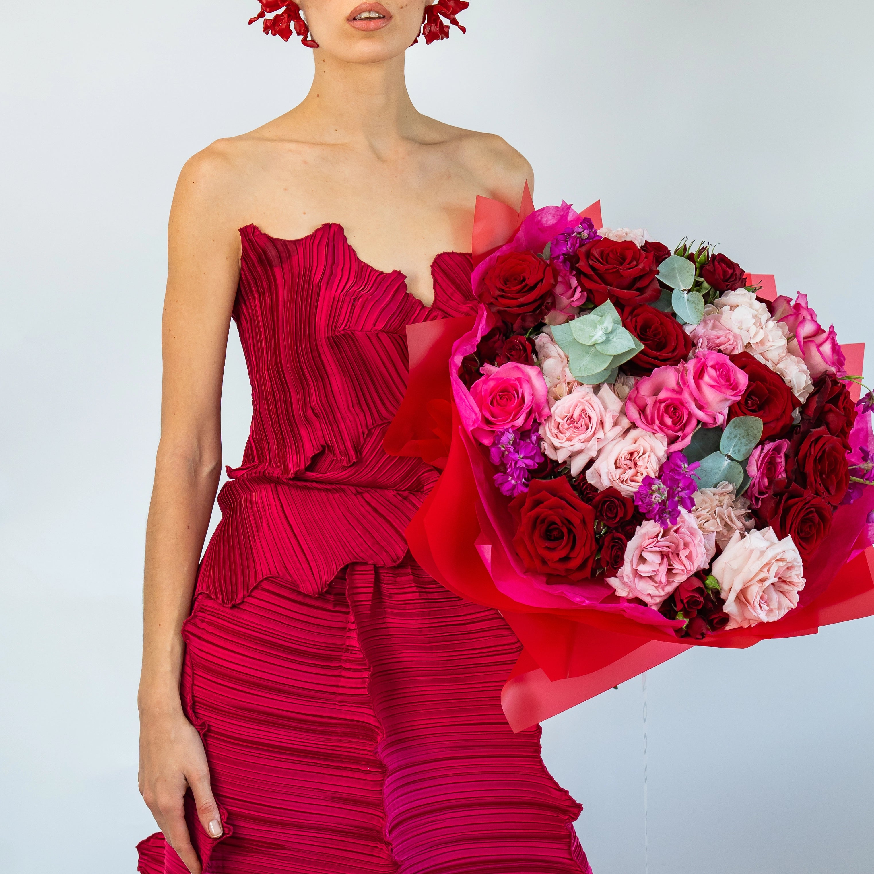 Red and pink rose bouquet with blush carnations and eucalyptus wrapped in bright pink paper for Valentine's Day