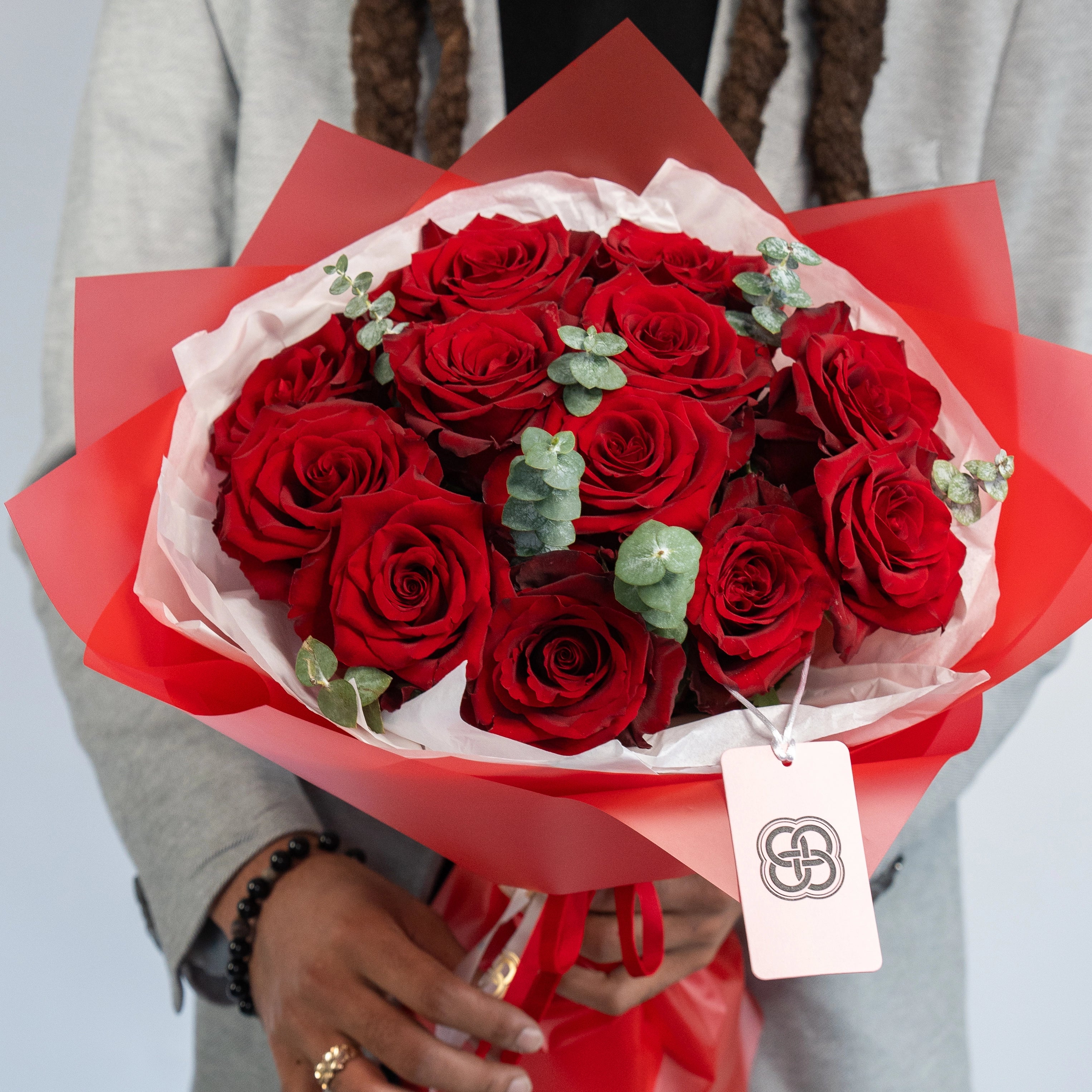 Deep red rose bouquet with eucalyptus leaves wrapped in red and white paper, perfect for Valentine's Day