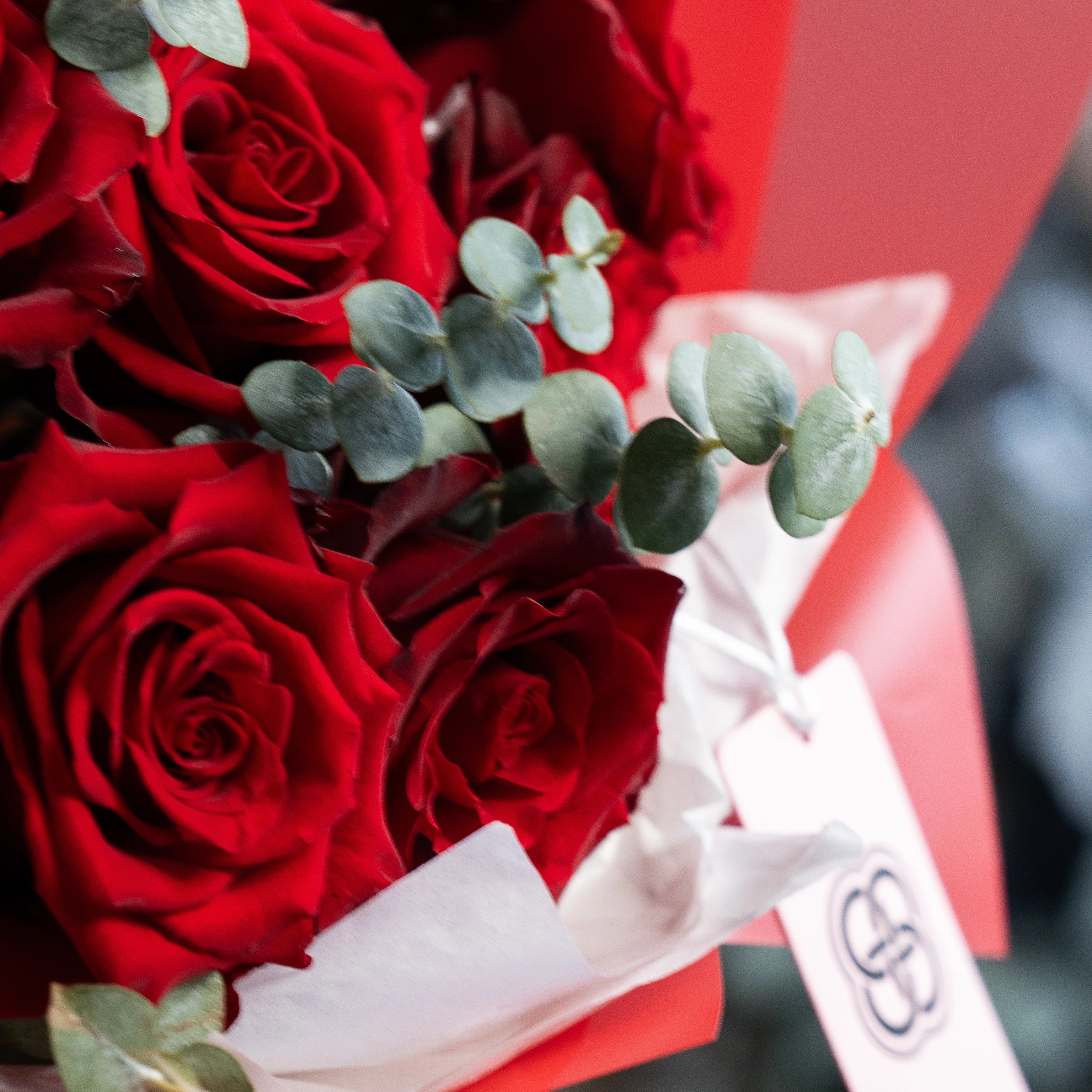 Red rose bouquet with eucalyptus leaves and white satin ribbon for Valentine's Day delivery in Los Angeles