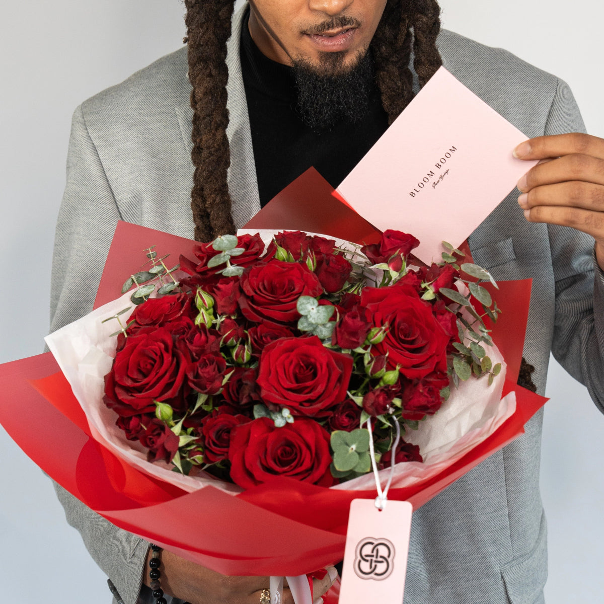 Luxury red rose bouquet with eucalyptus wrapped in red and white paper with pink greeting card