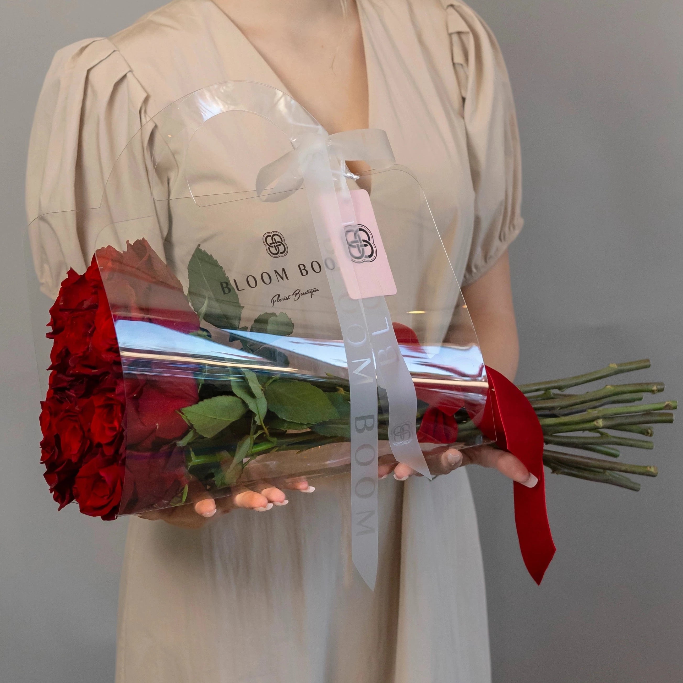 Red roses in clear acrylic gift box with white ribbon and Bloom Boom branding, perfect Valentine's Day gift