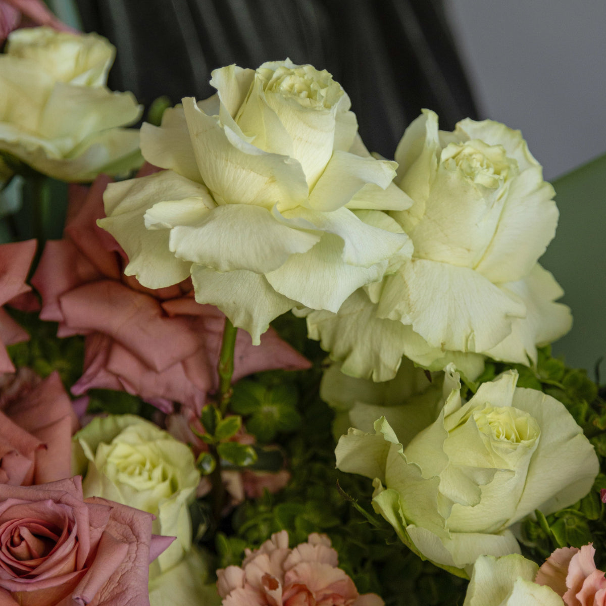 Pale yellow roses and dusty pink roses with green foliage in mixed flower bouquet arrangement